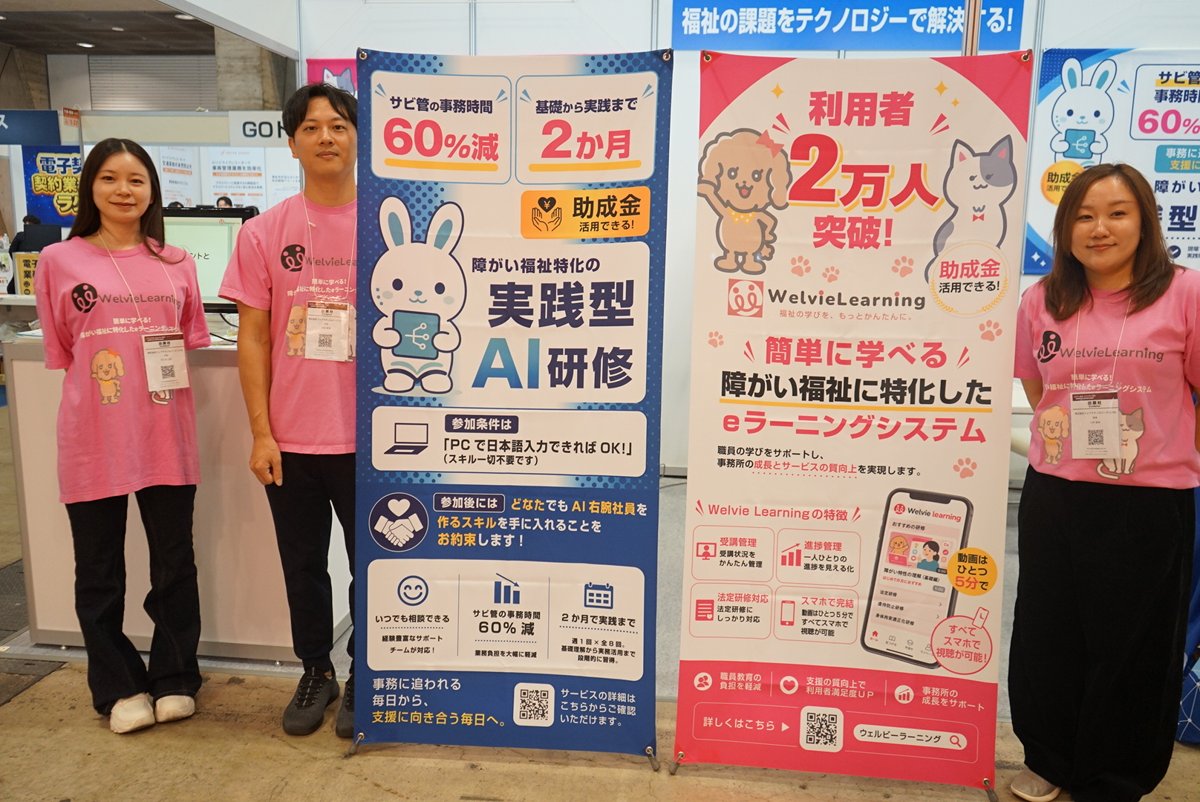 ウェルビーラーニングとWelvieAIのパネルの前に立つ出展スタッフ